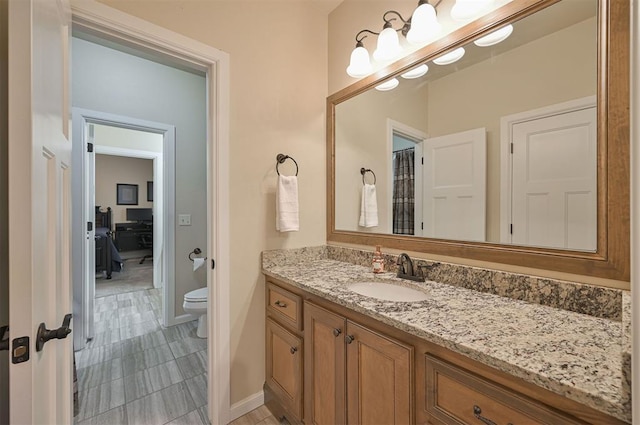 bathroom featuring toilet, vanity, and baseboards