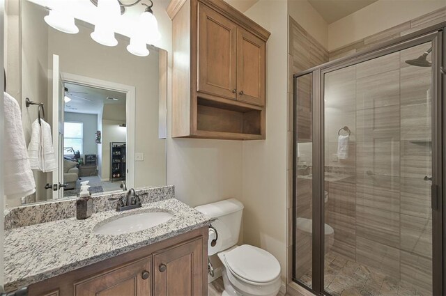 bathroom featuring a stall shower, toilet, vanity, and ceiling fan