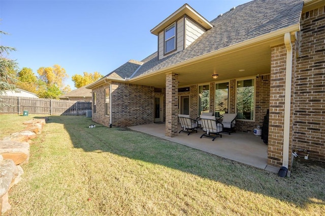 exterior space with a patio area, fence, brick siding, and a lawn