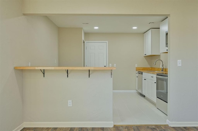 kitchen featuring white cabinetry, a breakfast bar, kitchen peninsula, and appliances with stainless steel finishes