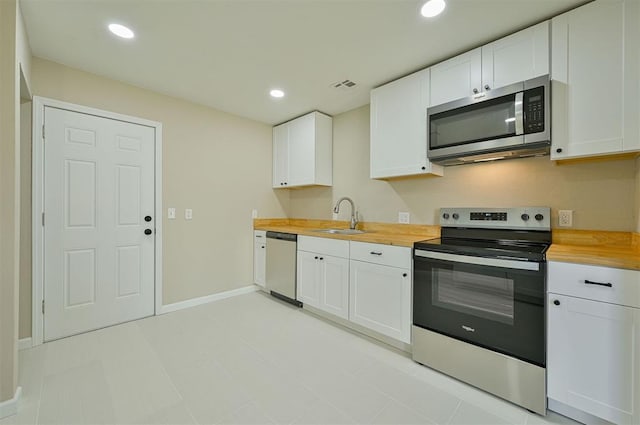 kitchen with stainless steel appliances, butcher block counters, and white cabinets