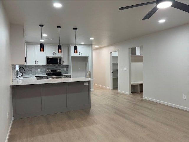 kitchen featuring kitchen peninsula, hanging light fixtures, white cabinets, and stainless steel appliances