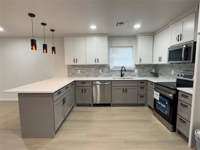 kitchen featuring gray cabinetry, sink, kitchen peninsula, and stainless steel appliances