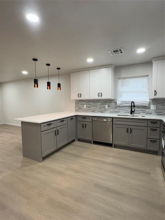 kitchen featuring white cabinetry, dishwasher, sink, kitchen peninsula, and pendant lighting