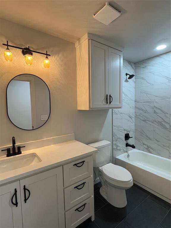 full bathroom with tile patterned floors, vanity, tiled shower / bath combo, and toilet