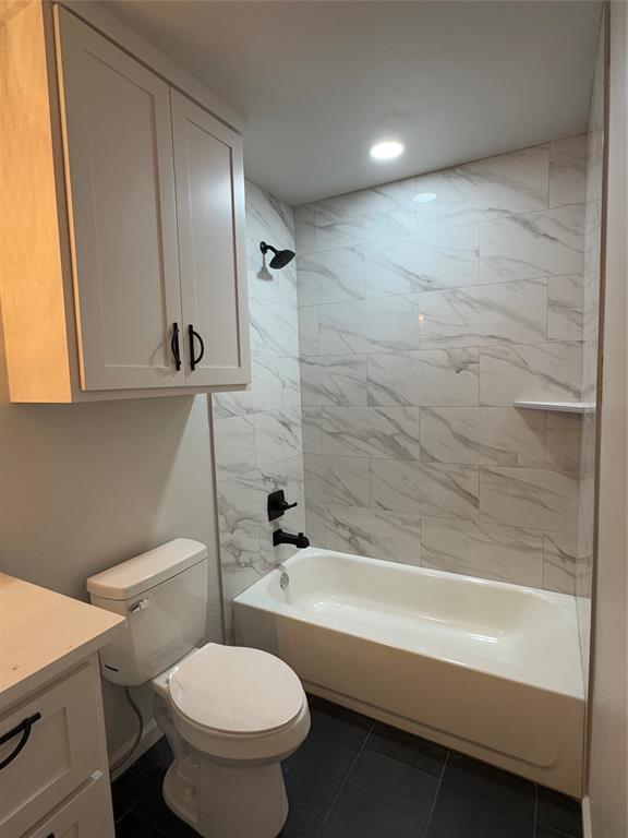 full bathroom featuring tile patterned flooring, vanity, toilet, and tiled shower / bath