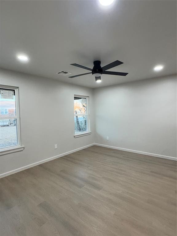 unfurnished room featuring ceiling fan, a healthy amount of sunlight, and hardwood / wood-style flooring