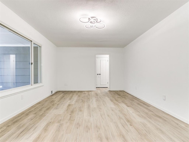 unfurnished room with light hardwood / wood-style floors and a textured ceiling