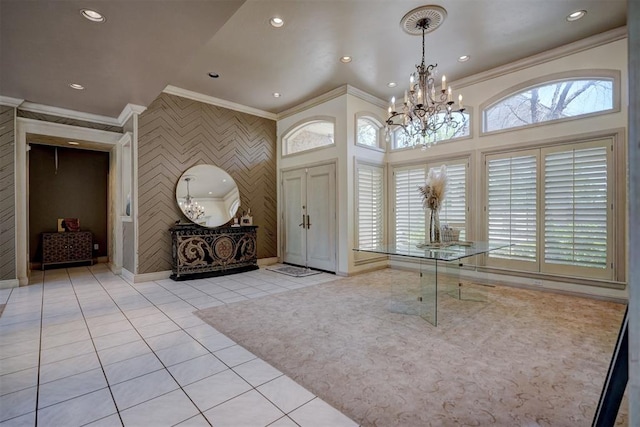 tiled entryway featuring a notable chandelier and ornamental molding