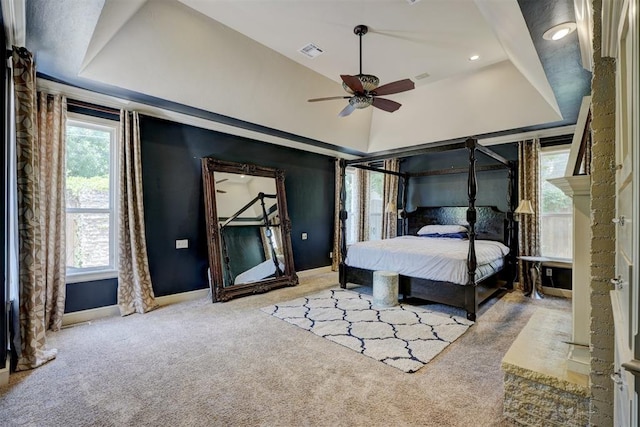 bedroom with a raised ceiling, ceiling fan, and light carpet