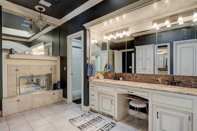 bathroom featuring tile patterned floors, vanity, crown molding, and a tile fireplace