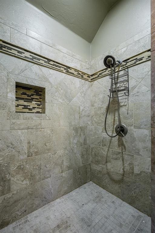 bathroom with a tile shower and vaulted ceiling