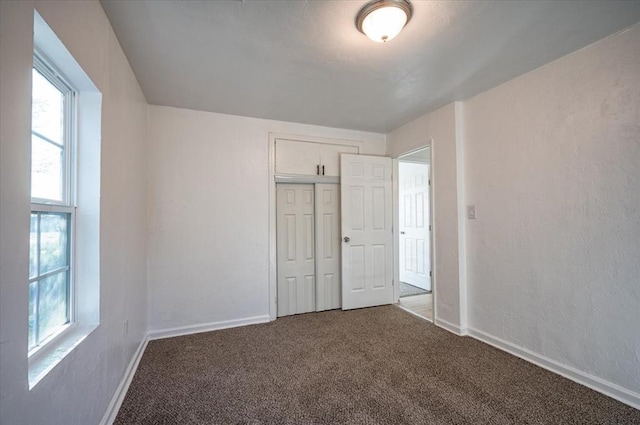 unfurnished bedroom featuring dark carpet and a closet