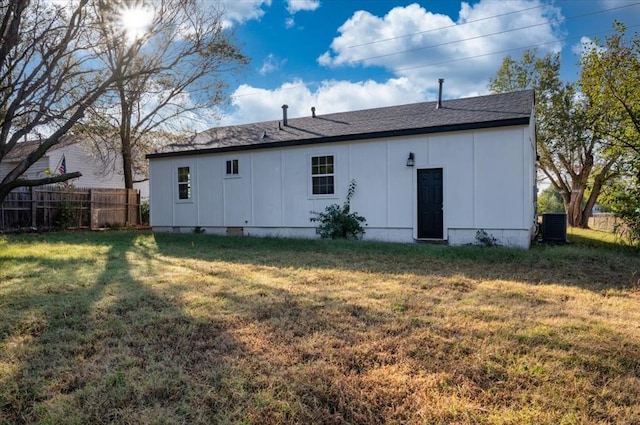 back of property with a yard and central AC