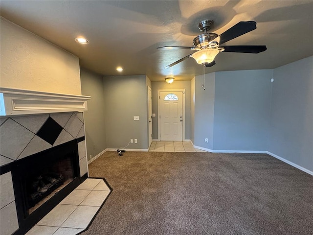 unfurnished living room with a tile fireplace, light colored carpet, and ceiling fan