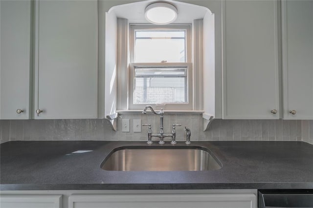 kitchen featuring white cabinets, decorative backsplash, stainless steel dishwasher, and sink