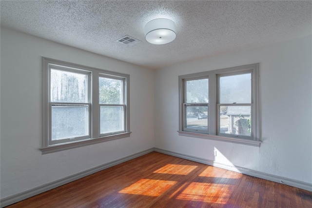 spare room featuring a textured ceiling and hardwood / wood-style flooring