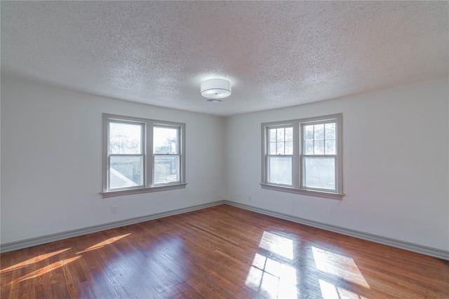 spare room featuring dark hardwood / wood-style floors and a textured ceiling