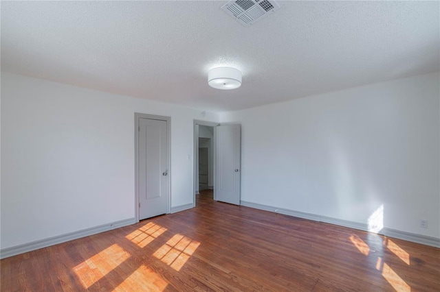 spare room featuring a textured ceiling and dark wood-type flooring