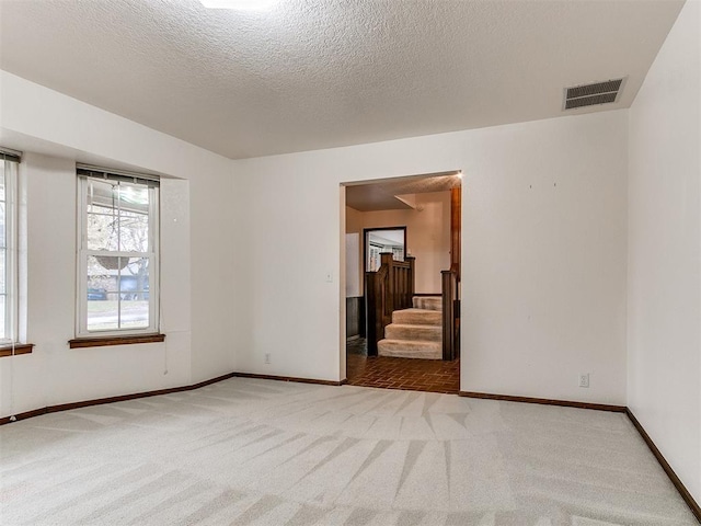 spare room featuring carpet floors and a textured ceiling