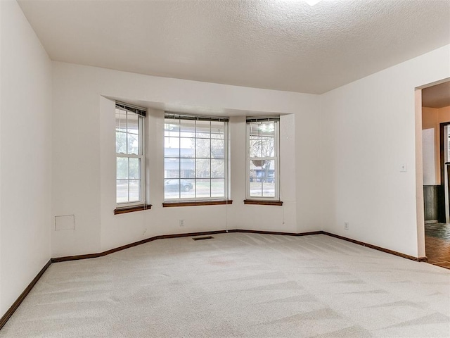 carpeted spare room featuring a textured ceiling