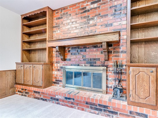 unfurnished living room with carpet, a brick fireplace, and wooden walls