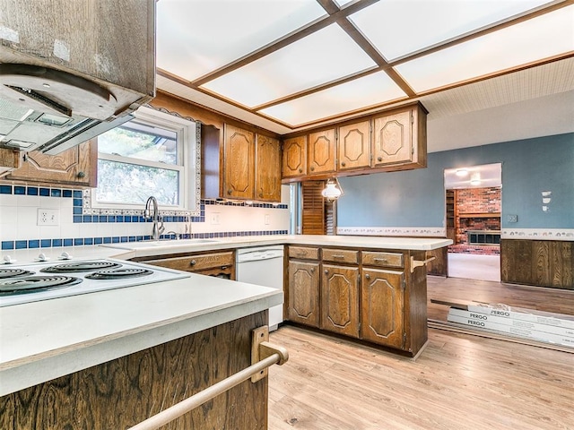 kitchen with sink, light hardwood / wood-style flooring, kitchen peninsula, white appliances, and decorative backsplash