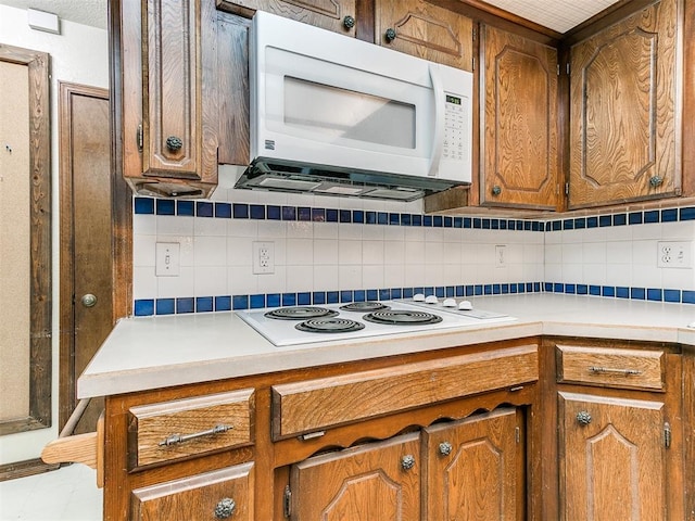 kitchen featuring decorative backsplash and white appliances