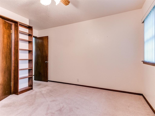 unfurnished bedroom with a textured ceiling, light colored carpet, and ceiling fan