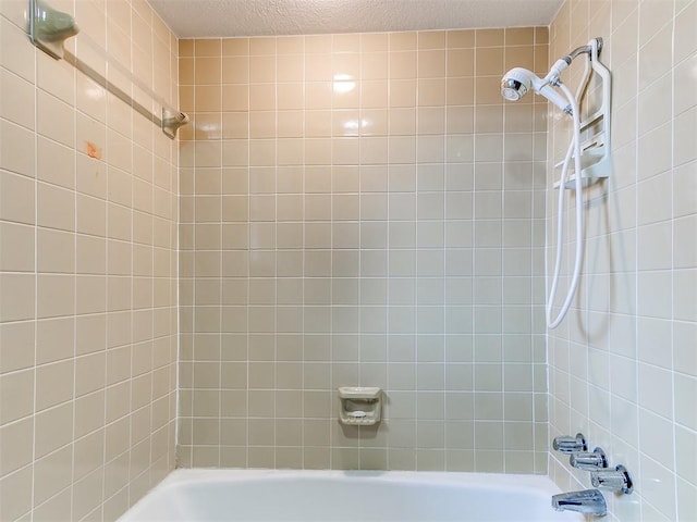 bathroom featuring a textured ceiling and tiled shower / bath combo