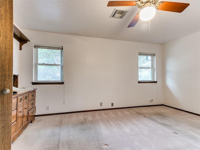 spare room with ceiling fan and light carpet