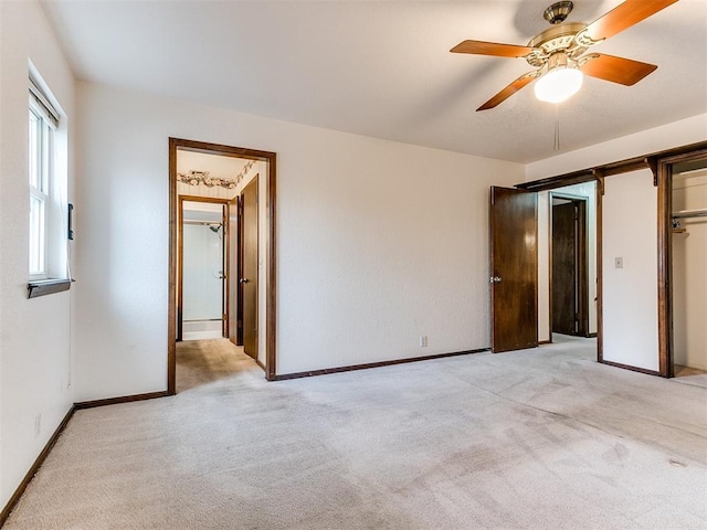 unfurnished bedroom featuring ensuite bathroom, ceiling fan, light carpet, and a closet