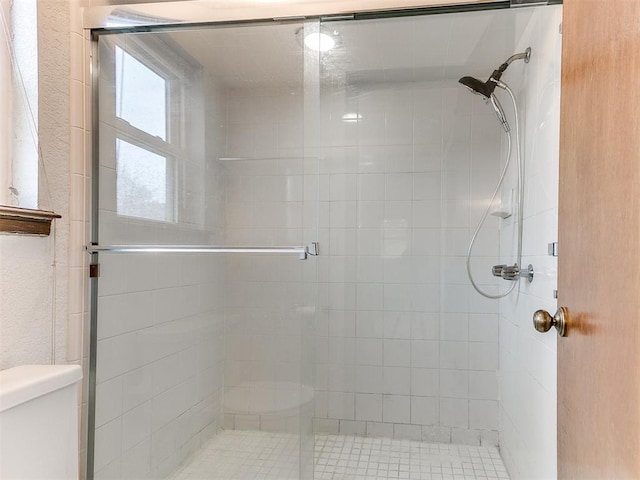 bathroom featuring toilet and a shower with shower door