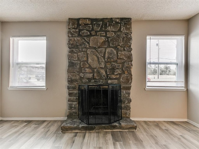 details featuring a stone fireplace, wood-type flooring, and a textured ceiling