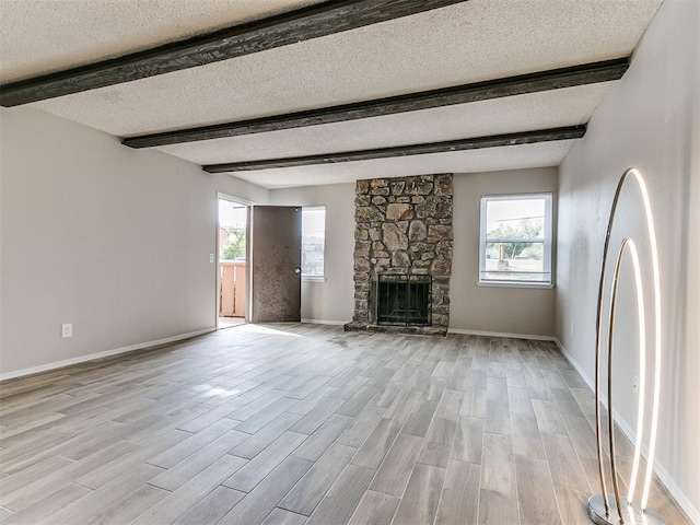 unfurnished living room featuring light hardwood / wood-style flooring, a textured ceiling, a fireplace, and a healthy amount of sunlight