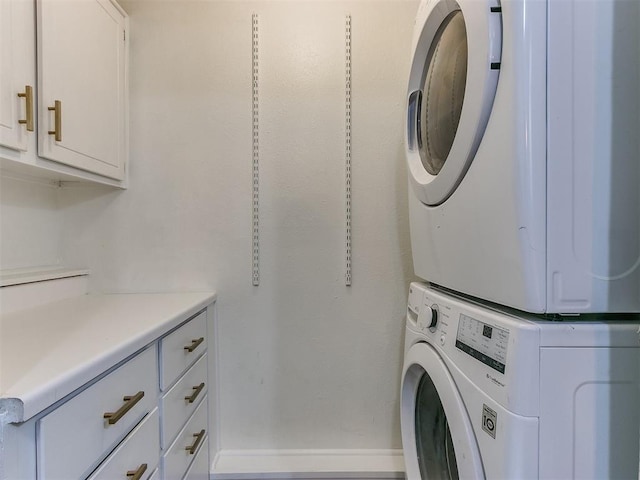 laundry room featuring cabinets and stacked washing maching and dryer