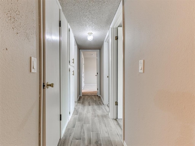 corridor featuring light hardwood / wood-style floors and a textured ceiling