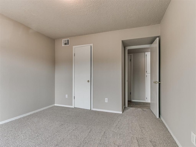 unfurnished bedroom featuring light carpet and a textured ceiling