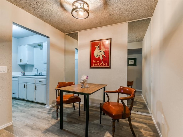 dining area with wood tiled floor, a textured ceiling, and baseboards