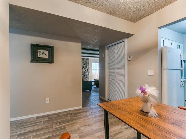 dining space with a textured ceiling, wood finished floors, and baseboards