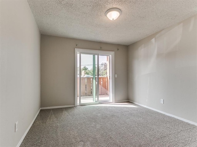 carpeted empty room featuring a textured ceiling and baseboards