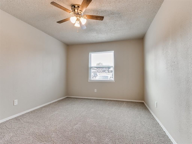 carpeted empty room with ceiling fan, a textured ceiling, and baseboards