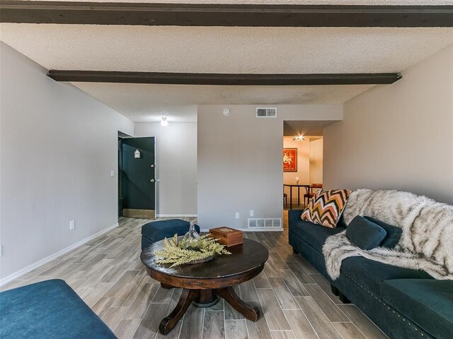 living room with beam ceiling, wood finish floors, and visible vents