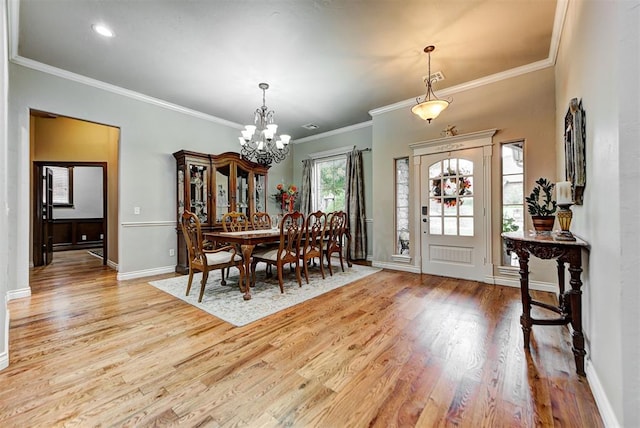 dining room featuring light wood-type flooring, ornamental molding, and a notable chandelier