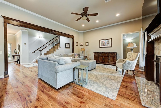 living area with stairs, baseboards, light wood-type flooring, and ornamental molding