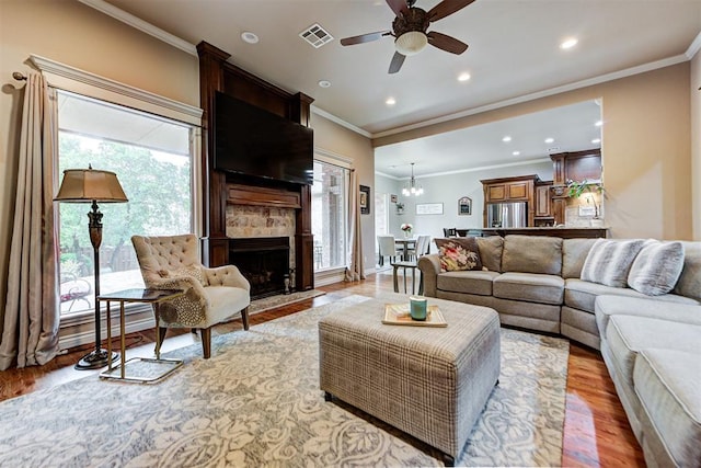 living area with visible vents, light wood-style flooring, recessed lighting, a large fireplace, and crown molding