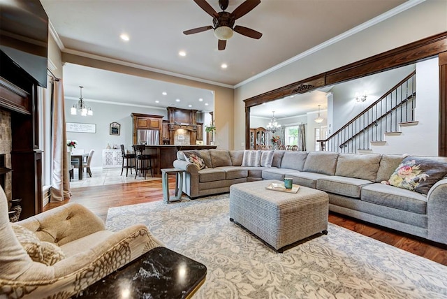 living room featuring ceiling fan with notable chandelier, light hardwood / wood-style flooring, and ornamental molding