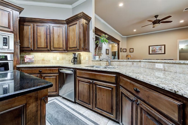 kitchen with light stone countertops, ornamental molding, decorative backsplash, appliances with stainless steel finishes, and a sink