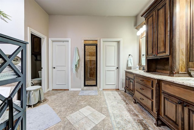 bathroom with tile patterned flooring, vanity, toilet, and walk in shower