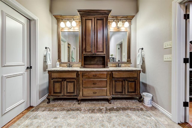 full bathroom with double vanity, baseboards, and a sink